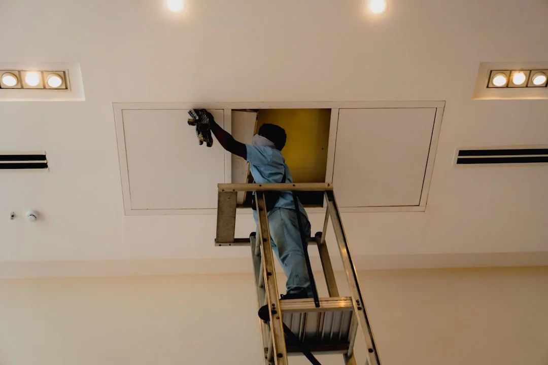 Person in PPE disinfecting indoor window area during COVID-19 pandemic.