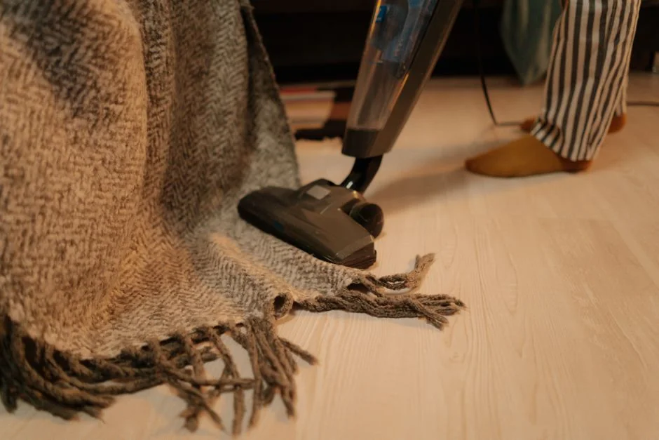 A person in full PPE disinfecting a table indoors for hygiene and safety.